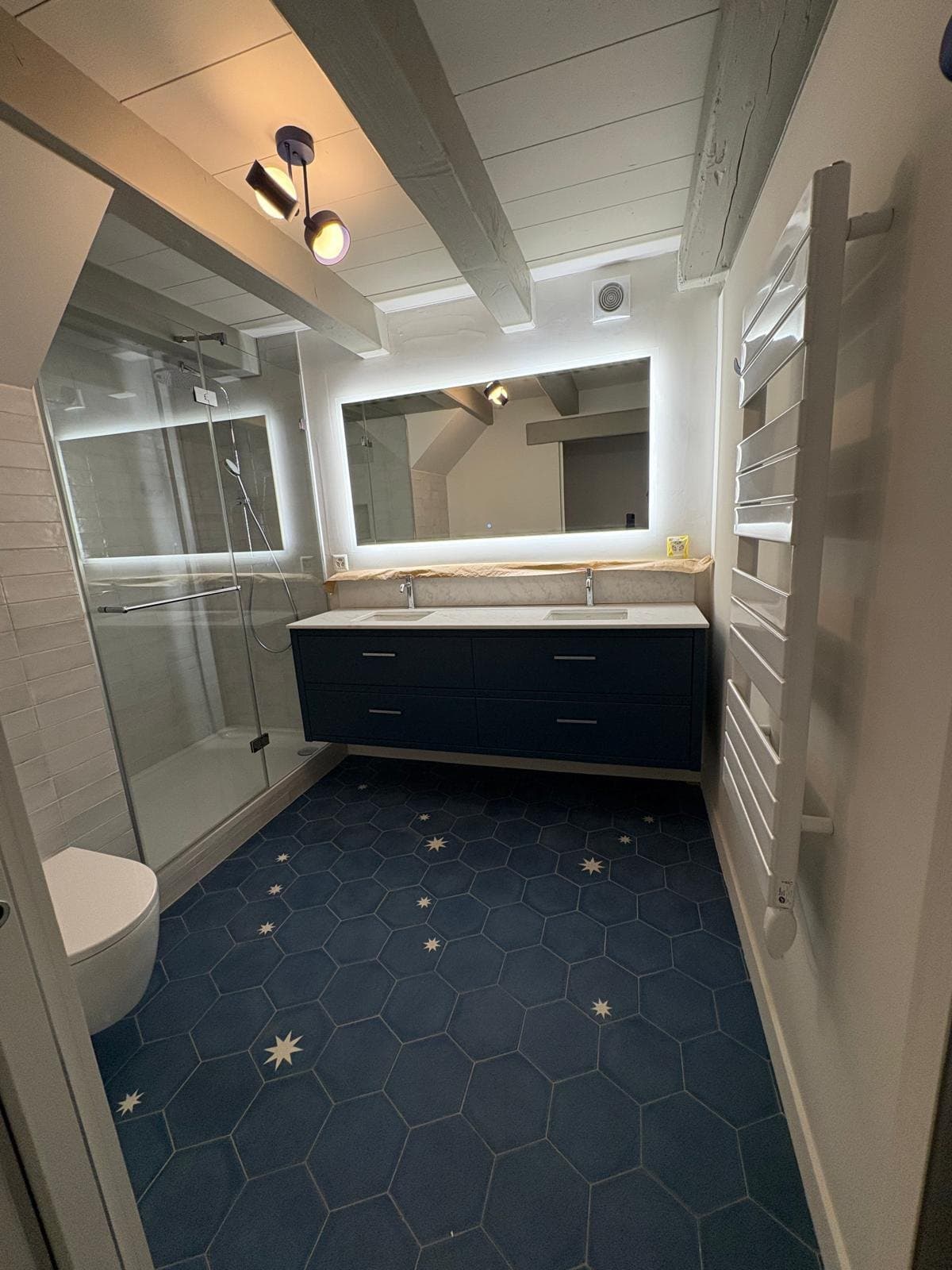 Salle de bain à Chéserex, meuble double vasque bleu nuit et sol en carreaux de ciment à étoiles