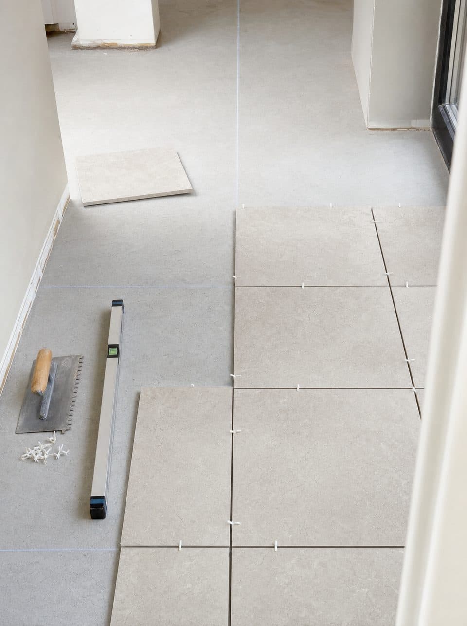 Carreaux grand format disposés à blanc et tracés à la craie pour planifier la pose